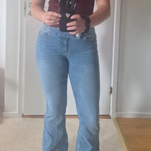 Ljusblå bootcut jeans - Säljer ett par ljusblå jeans med bootcut-modell och låg midja.Jeansen har klassisk femficksdesign och är tillverkade i mjukt denimtyg som sitter snyggt över höfterna och låren innan de släpper ut vid bensluten. Perfekta för dig som gillar retrovibbar och bekväm passform.