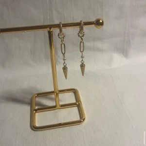Guldiga örhängen med kedjor och pärlor - Snygga guldiga örhängen med små hoops, kedjelänkar och vita pärldetaljer. Hängande spetsiga hängen ger en edgy vibe. Perfekta för dig som vill sticka ut med coola accessoarer. Passar till både street och trendiga looks.