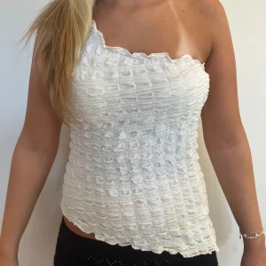 Vit oneshoulder tubtopp med struktur - Superfin vit topp med oneshoulder-design och vågig kant.