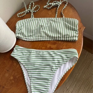 Grönvit randig bikini med knyt - Snygg bikini med gröna och vita ränder. Toppen har raka band och knyt vid axlarna för en justerbar passform. Klassiska bikinitrosor med samma randiga mönster. Oanvänd 