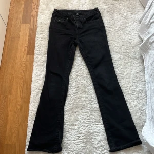 Svarta True Religion bootcut jeans - Svarta jeans från True Religion, modell Becca Mid Rise Bootcut. Klassisk femficksdesign med snygga detaljer på bakfickorna och bootcut-ben. Jeansen är i stretchig bomullsblandning och har en midwaist-passform. Perfekta för dig som gillar en tidlös och cool look.