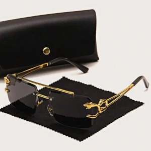 Svarta solglasögon med gulddetaljer - Stilrena solglasögon med svarta, rektangulära glas och tunna guldfärgade bågar. Snygga detaljer med lejonhuvuden på sidorna och svarta skalmar. Perfekta för dig som vill sticka ut med en lyxig och modern look. PRISET KAN DISKUTERAS!