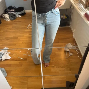  ljusblå jeans med straight fit - Säljer ett par klassiska jeans i ljusblå tvätt. De har medel hög midja, raka ben och femficksdesign. Jeansen är i jeansmaterial och har en snygg vintagekänsla. Perfekta för en chill och trendig look.