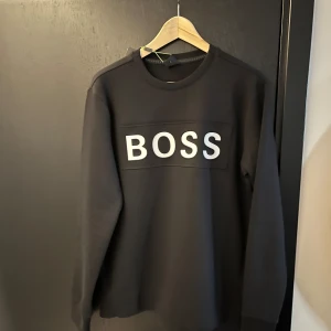 Boss sweatshirt svart - Snygg och enkel sweatshirt från boss. Helt ny och har fortfarande kvar lapparna. Storleken är S men kan också funka för M. Hör av er om ni har frågor.