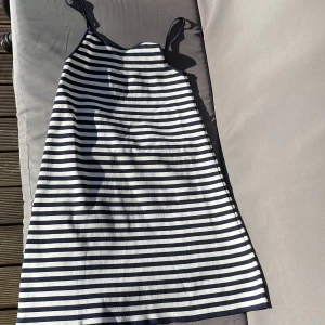 Randig sommarklänning från MNG - Supersöt kortklänning från MNG med marinblå och vita ränder. Klänningen har smala axelband och en rak, avslappnad passform. Perfekt för varma dagar och enkel att styla med sneakers eller sandaler.