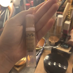 NYX Bare With Me Concealer Serum - NYX Bare With Me Concealer Serum i en smidig pumpflaska. Ljusbeige nyans med krämig formula som smälter in i huden. Perfekt för att täcka mörka ringar och ojämnheter. Innehåller 9,6 ml och passar dig som vill ha ett naturligt resultat.