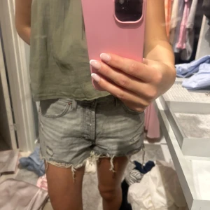 Zara shorts - Snygga grå jeansshorts med slitna detaljer och fransig kant nertill. Klassisk femficksmodell med bälteshällor och dragkedja. Perfekta för sommaren och ger en avslappnad vibe.