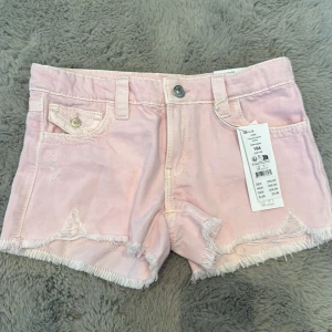 Ljusrosa jeansshorts från Gina Tricot - Snygga ljusrosa jeansshorts från Gina Tricot med fransig kant och slitna detaljer. Är lågmidjade. Oanvända 