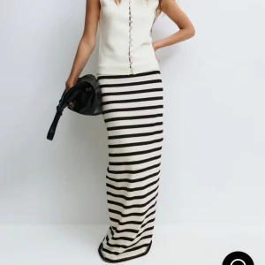 Randig långkjol i stickad bomull - Säljer en superfin långkjol från Gina i storlek S som är helt slutsåld. med svart och krämvita ränder. Kjolen är stickad och har en rak, figurnära passform som ger en clean och trendig look. Nypris är 399, och den är helt oanvänd med lapp på.