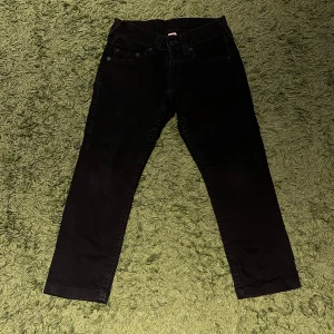 Svarta True Religion jeans, stl 27 - Svarta jeans från True Religion i klassisk femficksmodell. Snygg, smal passform med raka ben och diskreta sömmar. Tidlös design med svart patch bak i midjan. Perfekta till sneakers eller boots.