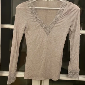 Inga defekter som ny!!! Intimissimi lace top ultra Kashmir  - Supersöt ljusgrå långärmad topp med v-ringning och fina spetsdetaljer både vid halsringningen och vid ärmsluten. Toppens material känns mjukt och stretchigt, perfekt för en chill men ändå stilren look.
