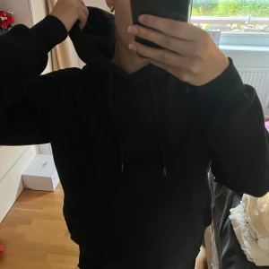 Svart hoodie  - Svart hoodie i regular fit med klassisk huva och dragsnören. Tröjan har en stor magficka och långa ärmar. Efter många gångers användning och därmed tvättar har materialet på nästan hela hoodien blivit lite noppigt, i helhet ser den ändå bra ut på, särskilt eftersom den ät svart och det noppiga inte syns lika mycket 🥰