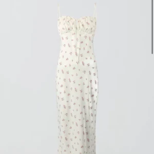 Vit blommig långklänning med smala band - Superfin långklänning i vit med små rosa blommor från Gina,  Klänningen har smala axelband, söt snörning vid bysten och en figurnära passform. Perfekt för sommaren💗.             Klänningen går inte längre att köpa och är endast använd 1 gång därför säljer jag den för 300kr. Nypris -499kr