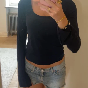 Mörkblå långärmad topp Gina Tricot - Säljer en mörkblå långärmad topp från Gina Tricot med snygg, djup rundad urringning och slits vid ärmarna. Modellen är figurnära och har långa ärmar. Perfekt att styla med jeans eller kjol. 