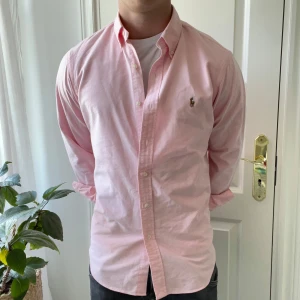 Ralph Lauren skjorta rosa  - En rosa Ralph Lauren skjorta i nyskick! 10/10 skick. Modellen är 180,75 kg och bär M. Den är nästan lite för stor för honom och är en väldigt stor M. Kom med frågor! Funkar väldigt bra som en overshirt också. MVH 