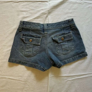 Blå jeansshorts  - Blå jeansshorts med knappar på bakfickorna och stora framfickor💙 midjemått: 34cm