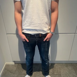 Marinblått flätat bälte med skinn från Tressé - Snyggt marinblått flätat bälte från tressé med bruna skinn-detaljer och silverspänne. Perfekt accessoar för att lyfta din outfit med en klassisk touch. Bältet har en stilren design med kontrastsömmar på skinnet. Finns inte många kvar så skynda!!