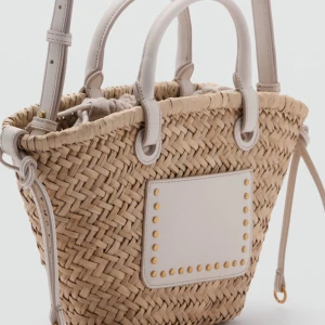 Korgväska med vita detaljer - Slutsåld på mangos hemsida!! Snygg flätad handväska i beige med vita handtag och detaljer. Väskan har en vit skinnplatta framtill med guldfärgade nitar och långt band till. 