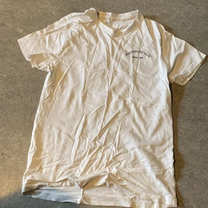 Vit t-shirt från 157 med tryck - Vit t-shirt från 157 med liten svart text 'Speed Racquet Club Since 1989' på bröstet. Klassisk rund hals och korta ärmar. Skön och enkel modell i bomull, perfekt till jeans eller shorts.