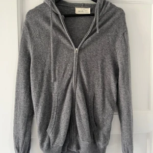 Grå hoodie med dragkedja från Zara Origins - Mysig grå cashmere hoodie från Zara Origins i storlek S. Tröjan har dragkedja framtill, huva med snören och två fickor. Perfekt för lager-på-lager och enkel att matcha med det mesta.