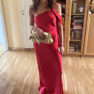 Röd långklänning med oneshoulder - Säljer en elegant röd långklänning med oneshoulder-design. Klänningen har en slät och glansig yta som ger en lyxig känsla. Perfekt för speciella tillfällen när du vill sticka ut och känna dig extra fin. Endast använd en gång! 