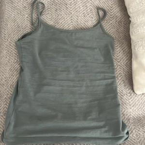 Grå linnetopp från Amisu - Säljer en stilren grå linnetopp från Amisu i storlek XS. Toppen har tunna, justerbara axelband och är tillverkad i ett mjukt, slätt material som ger en snygg och enkel look.