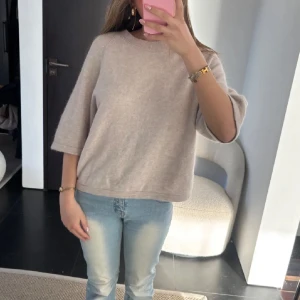 Beige stickad tröja från & Other Stories - Säljer en supermjuk och stilren beige stickad tröja från & Other Stories. Tröjan har trekvartsärm, rund halsringning och en avslappnad passform. Perfekt att styla med jeans eller kjol för en enkel men snygg look.