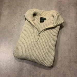 Tröja från Calvin Klein - Säljer en beige, ribbstickad tröja från Calvin Klein Jeans med halv dragkedja och hög krage. Tröjan har lång ärm och logotyp på ena ärmen. Perfekt för kyligare dagar och enkel att matcha. Tröjan är i bra skick och i storlek herr XL. Bara att höra av sig vid funderingar!