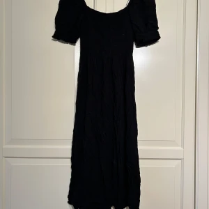 Svart långklänning med puffärm från H&M - Säljer en svart långklänning från H&M med puffärmar. Klänningen har en feminin siluett och är tillverkad i ett mjukt bomullstyg. Perfekt för dig som gillar en klassisk och stilren look.