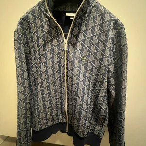 Blå mönstrad track jacket från Lacoste - Säljer en blå Lacoste zipup. Storlek M men passar S med. Priset kan diskuteras 
