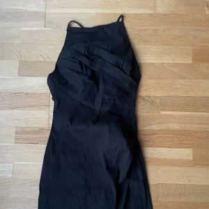 Svart omlottklänning från Zara - Säljer en svart omlottklänning från Zara i storlek XS. Klänningen har smala axelband och en elegant omlottdesign framtill. Perfekt för dig som gillar en stilren och tidlös look.