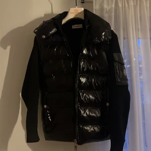 Svart cardigan från Moncler  - Säljer en svart cardigan från Moncler med glansig framsida och huva. Jackan har dragkedja, fickor med tryckknappar och Moncler-logga på ärmen. Ärmar och rygg är i ett annat tyg än framsidan vilket ger en snygg kontrast. Blipp på moncler tagen funkar också. Pris kan diskuteras 