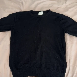 Svart stickad tröja från H&M - En klassisk svart stickad tröja från H&M i storlek XS. Tröjan har rund halsringning och långa ärmar, perfekt för lager-på-lager eller som den är. Enkel och stilren design som passar till det mesta.