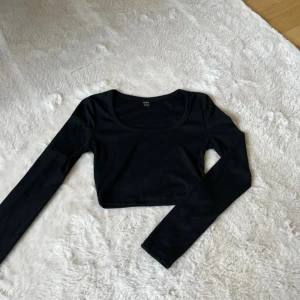 Svart croppad långärmad topp - Säljer en svart croppad topp med lång ärm och rundad urringning. 