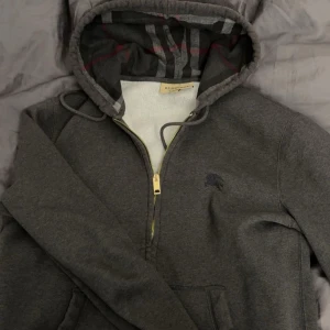 Mörkgrå ÄKTA burberry hoodie - Säljer min mörkgråa  burberry hoodie som självklart är äkta. Köptes på ett outlet i Spanien. Har dessvärre inget kvitto eller liknande.