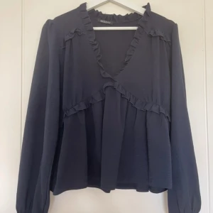 Marinblå volang blus  - Säljer en marinblå blus, mycket bra skick, typ som ny! Strl M, från missay, säljer den för 80kr + frakt!