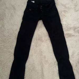 Svarta jeansbyxor från Pepe Jeans - Säljer ett par svarta jeansbyxor från Pepe Jeans med klassisk femficksdesign och knappgylf. Byxorna är raka i passform och har en låg midja. De är perfekta till många olika outfits. Snygga detaljer och diskret logga bak på linningen.