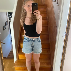 Ljusblå jeansshorts med fransar - Säljer ett par ljusblå jeansshorts medgång midja och råa franskantade benslut. Klassisk femficksmodell och knappgylf. Shortsen är aldrig använda