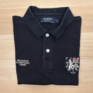Morris Piké Navy M - Klassisk mörkblå pikétröja från Morris med broderad logga och emblem på bröstet samt siffran 8 på ärmen. Tröjan har krage, knappar framtill och är tillverkad i bomull. Perfekt för en stilren och sportig look.