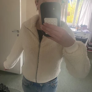 Vit teddyjacka med dragkedja - Mysig vit teddyjacka med dragkedja framtill och hög krage. Den är ifrån Gina, står storlek M fast tycker mer att den är S/Xs, pris går såklart att diskutera !💕