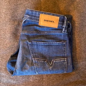 Diese Jeans - Blå jeans från Diesel. Jeansen har raka ben, fem fickor och en snygg läderpatch med Diesel-loggan bak.