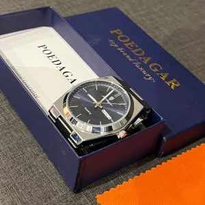 Poedagar silver herrklocka med blå urtavla. Oak 41mm - Stilren herrklocka från Poedagar med blå urtavla och dag/datumvisning. Klockan har ett silverfärgat armband i rostfritt stål och klassisk design. Perfekt accessoar för dig som gillar en elegant look och som letar en snygg klocka till sommaren. Inköpt från hugopdgr.com nyligen för  775kr. Klockan är använd ett fåtal gånger och är därför i nyskick👍🏻. Extra länkar följer med i köpet så att den går att justera.