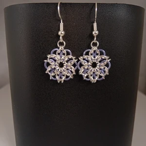 Egentillverkade örhängen  - Egentillverkade örhängen gjorda med bindringar i silverfärg och blå nyans. Öronkroken är nickelsäker och aldrig använda. Längd ca 3cm långa, blomman är ca 2 cm 