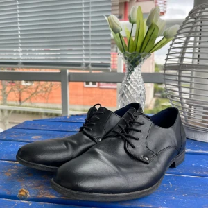 Svarta skinnloafers från iguassu - Stilrena svarta loafers i skinn från Guassu med klassisk snörning och rund tå. Perfekta för en dressad look och passar till många olika tillfällen. Snygg och enkel design med platt sula.