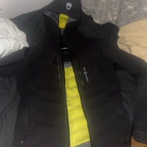 cardigan från sail racing  - Säljer en svart softshelljacka från Peak Performance med gul vadderad insida. Jackan har dragkedjor framtill och hög krage med logga. Perfekt för kyliga dagar och har en sportig look. dragkedjan kan va jobbig ibland därför priset ä så lågt