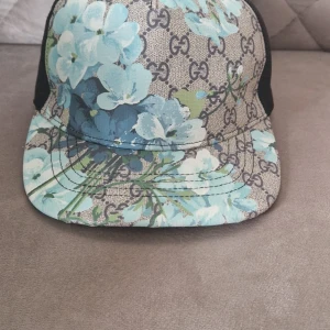 Gucci keps med blommigt mönster - Snygg keps från Gucci med blått blommönster på klassisk GG-logga. 