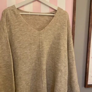 Beige stickad v-ringad tröja - Mysig beige stickad tröja med v-ringning och ribbade muddar.. Oversized passform för en avslappnad look. Denna är endast använd en gång, inga tecken på det. 