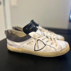 Vita sneakers från Philippe Model - Säljer ett par vita philip model skor med gråa detaljer och en beige sula. Skorna är i storlek 40 men dom är lite större i storleken så dom passar också till 41. Philip model skor har på Senaste tiden blivit mycket trendig. Säljer skorna för dom inte passar mig längre. Priset är 1300 med vid snabb affär kan pris diskuteras. 