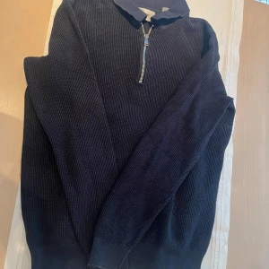 Mörkblå stickad tröja med dragkedja från Only & Sons - Säljer en mörkblå stickad tröja från Only & Sons med halv dragkedja och krage. Tröjan har lång ärm och är tillverkad i ett grovstickat material som ger en stilren och avslappnad look.