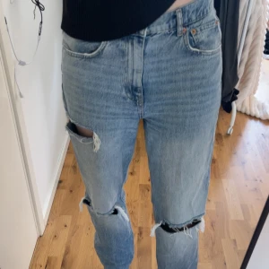 Ljusblå slitna jeans med hål - Säljer ett par ljusblå jeans med raka ben och flera slitningar, bland annat stora hål vid knäna och en mindre slitning bakfickan🤍 Är 175cm o de är ända ner till marken på mig🥰